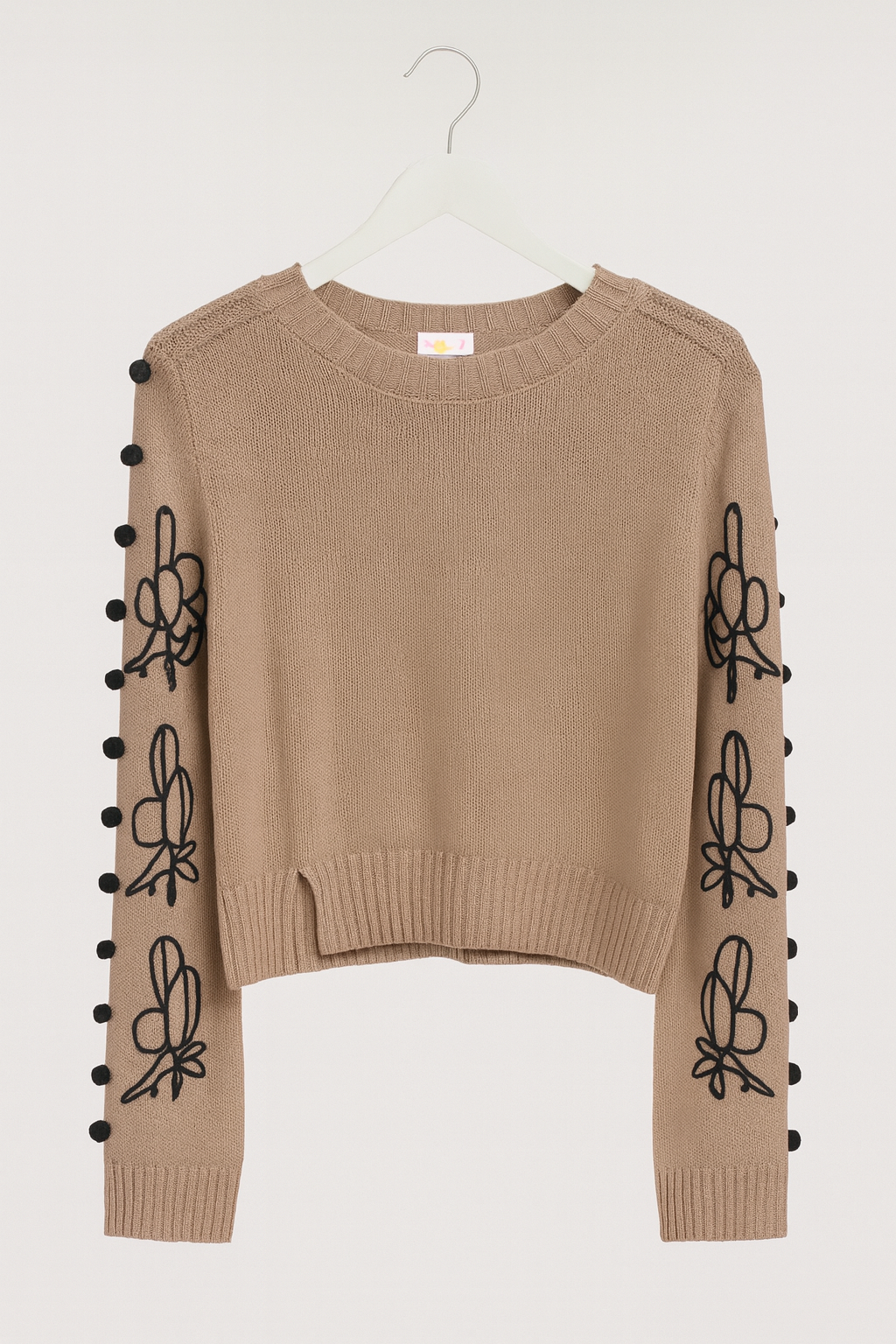 beige sweater with long, wide sleeves and black tassels