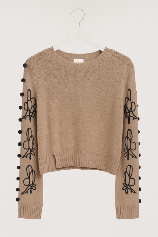 beige sweater with long, wide sleeves and black tassels